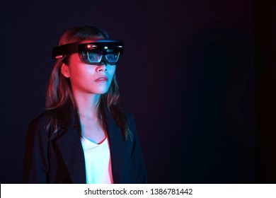Business woman try vr glasses hololens in the dark room. Portrait of young asian girl experience ar communication. Future technology concept.