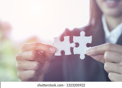Geschäftsfrau versucht ein paar Puzzleteile miteinander zu verbinden. Vereinigungszeichen und Verbindungszeichen. Konzept der Geschäftsstrategie