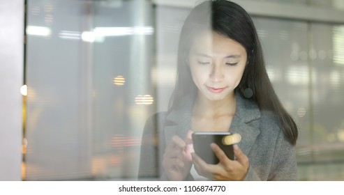 Business Woman Use Of Smart Phone In City With Window Reflection At Night