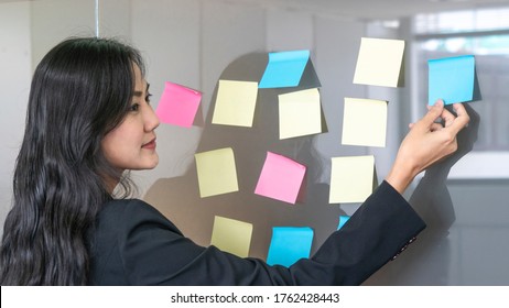 Business Woman Uses Paper Post Stick On Glass And Standing Front Of Glass War In Room With Nature Trees Background.