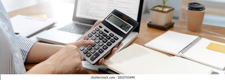 Business Woman Using Calculator Analyzing Data Report At Home.