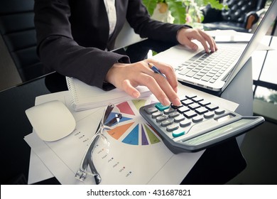 Business woman using a calculator to calculate the numbers on his desk in a office.