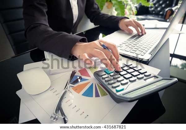 Mujer de negocios usando una calculadora para calcular los nÃºmeros en su escritorio en una oficina.