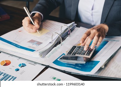Business woman using calculator and laptop for do math finance on wooden desk in office and business working background, tax, accounting, statistics and analytic research concept