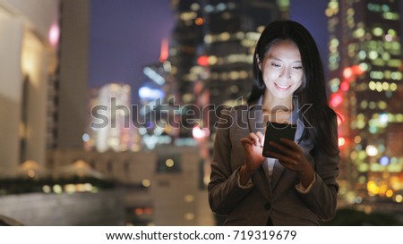 Business woman using cellphone in city at night 