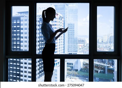 Business woman using her phone in a office setting.  - Powered by Shutterstock