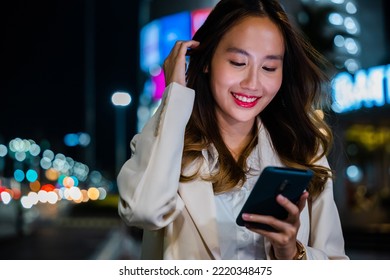 Business Woman Using Mobile Phone Walking Through Night City Street While Waiting Car To Pick Up Home, Beautiful Young Smiling Female Texting Work On Smartphone, Social Media