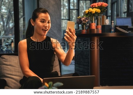 Business woman using a mobile phone for a distance face call and a laptop online