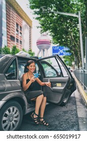 Business Woman Using Phone App For Mobile Payment Of Ride Share Black Cab Car. Rideshare Sharing Concept. Asian Businesswoman In Financial District Pudong, Shanghai, China.