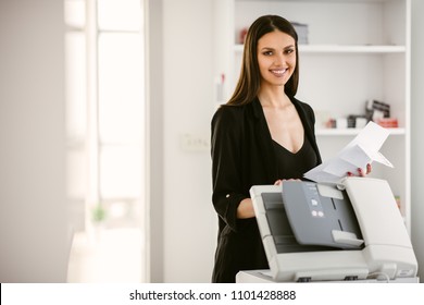 Business woman using a printer.
Beautiful business woman printing a document. 
Business woman printing a document for a new company project.