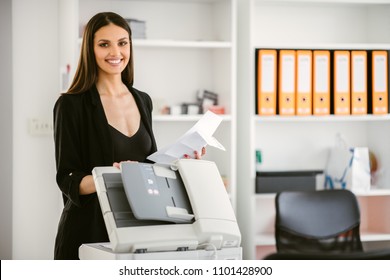 Business woman using a printer.
Beautiful business woman printing a document. 
Business woman printing a document for a new company project.