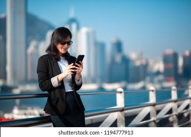 Business woman using the smartphone on waterfront in Hong Kong  - Powered by Shutterstock