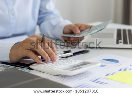 Business woman using a white calculator. She is analyzing the company's annual results in detail. In order to make the information accurate and complete without making any errors.