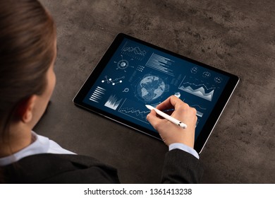 Business woman verifying reports on tablet with pencil in business suit
