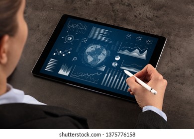 Business woman verifying reports on tablet with pencil in business suit