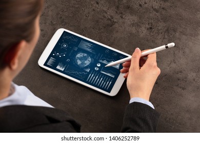 Business woman verifying reports on tablet with pencil in business suit
