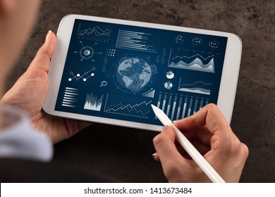 Business woman verifying reports on tablet with pencil in business suit
