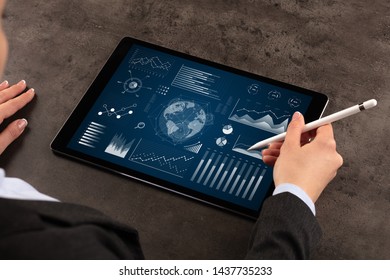 Business woman verifying reports on tablet with pencil in business suit