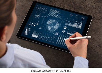 Business woman verifying reports on tablet with pencil in business suit