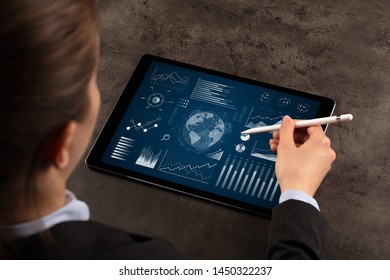 Business woman verifying reports on tablet with pencil in business suit