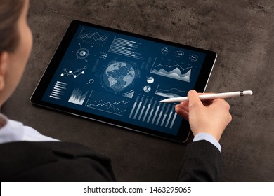 Business woman verifying reports on tablet with pencil in business suit