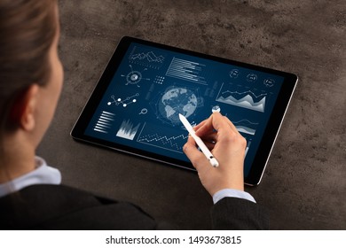 Business woman verifying reports on tablet with pencil in business suit