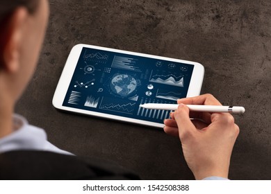 Business woman verifying reports on tablet with pencil in business suit