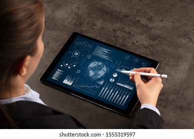 Business woman verifying reports on tablet with pencil in business suit