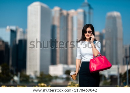 Business woman walking in city with coffee and smartphone on hand