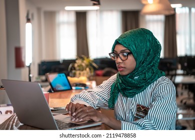 Business woman wearing a green hijab using laptop in relaxation area at modern open plan startup office. Selective focus  - Powered by Shutterstock