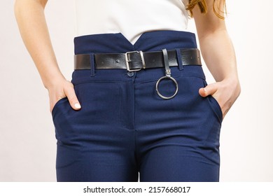 Business woman wearing suit, blue high waist pants with black leather trouser belt. Clothing detail.