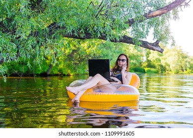 Business woman working on a laptop and talking on smartphone in an inflatable ring in the water, a copy of the free space. Workaholic, work on vacation. - Shutterstock ID 1109991605
