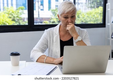 Business Woman Working On Laptop Computer In Modern Home Office.  Senior Woman Serious Working On Laptop. Serious Mature Older Adult Woman Watching On Laptop Working From Home.