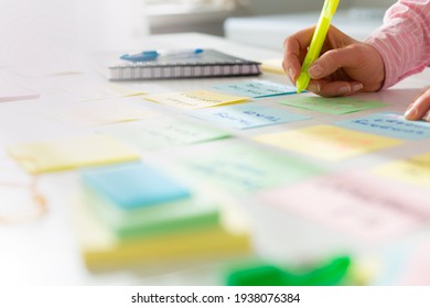 Business woman working on a project using sticky notes on her desktop. Brainstorming to find new development ideas and company strategies.