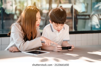 Business Woman Working Online In Cafe With Kid. Asian Family Lifestyle With Mobile Phone And Digital Tablet.