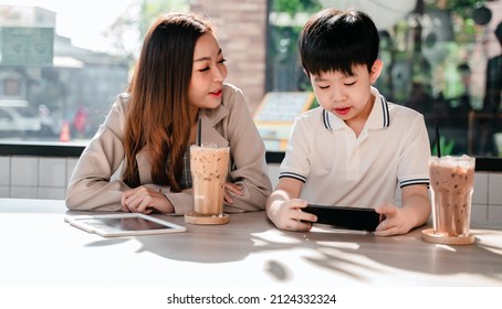 Business woman working online in cafe with kid. Asian family lifestyle with mobile phone and digital tablet.