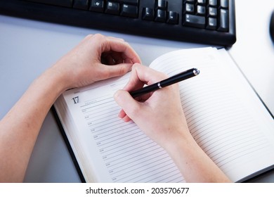 business woman in the workplace does records in a diary - Powered by Shutterstock