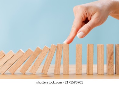 Business Woman's Finger Try To Stopping Falling Wooden Dominoes Blocks For Business Solution Concept. Business Crisis Effect Or Risk Protection Concept