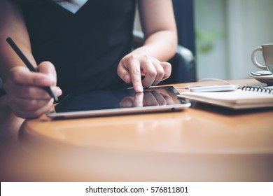 A Business Woman's Hands Using Tablet With Smart Phone , Earphone  And Notebook On Wooden Table