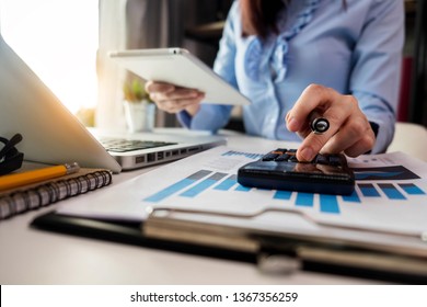 Business Women Calculates Financials With Graph Paper On The Table On The Cost Of Home Office.