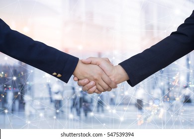 business women handshake agreement on blurred double exposure of city urban metropolis and connecting line technology effect background,ceo financial advisor hand shake together.