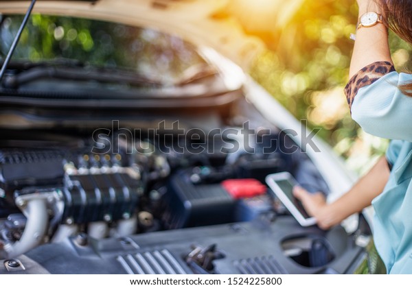 Business women have car problems on the side of the\
road.The light is golden at sunset. Young women calling car\
mechanic. Concept of quality inspection of cars Engine maintenance\
all the time.