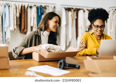 Business women launching an ecommerce site in a clothing boutique store, fulfilling their first few orders for drop shipping. Two women expanding their entrepreneurship with an online store.