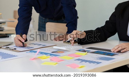 business women and men working together in groups in the office Everyone pointed together graph papers on conversation strategies and planned teamwork using data and calculators with laptops on the of