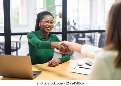 Business women shaking hands in the office during business meeting. Two diverse female entrepreneurs on meeting in boardroom. Female recruiter and employee confirm hiring - Powered by Shutterstock