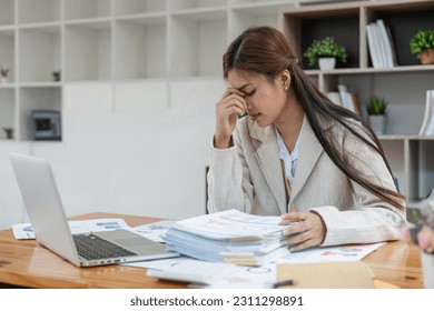 Business women are stressed while working on laptop and pile of documents, Tired businesswoman with headache at office, feeling sick at work - Shutterstock ID 2311298891