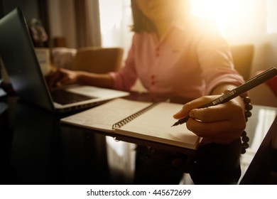 Business Women Using Laptop And Note Some Data On Notepad