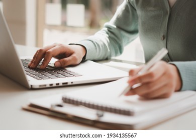 ビジネスマンは、コンピューターで働き、ペンでメモ帳に書き、オフィス内の財務諸表を計算します。