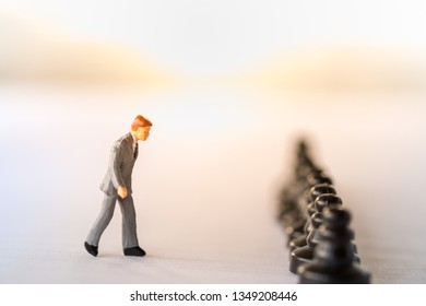 Business Work And Planning Concept. Close Up Of Businessman Miniature Figure Walking To Row Of Black Chess Pieces  On Notbook