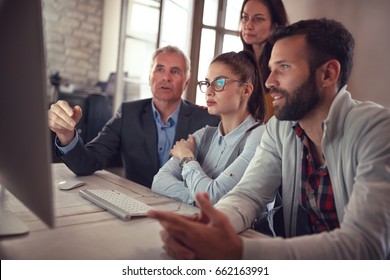 Business Workers In Discussion At Computer In Office
